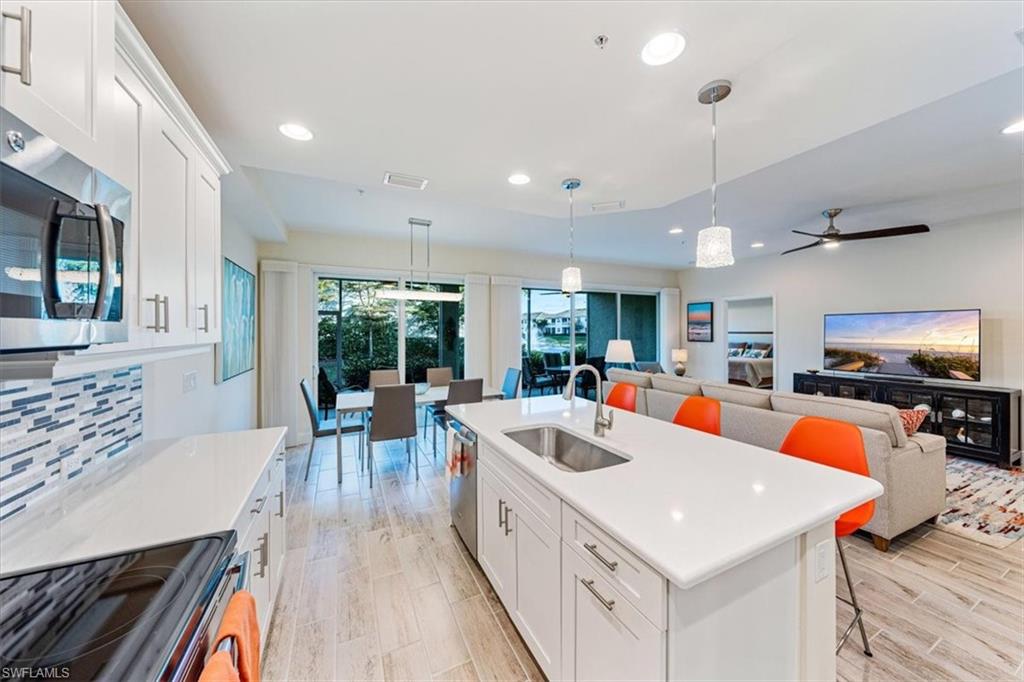 6934 Avalon Circle, Unit 402 Naples, FL 34112 - Photo 12 of 28 a large white kitchen with a large island attached withe living room