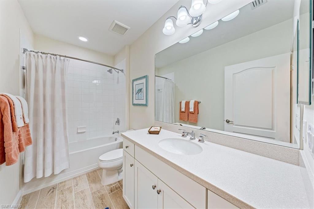 6934 Avalon Circle, Unit 402 Naples, FL 34112 - Photo 20 of 28 a bathroom with a granite countertop sink a toilet and a large mirror