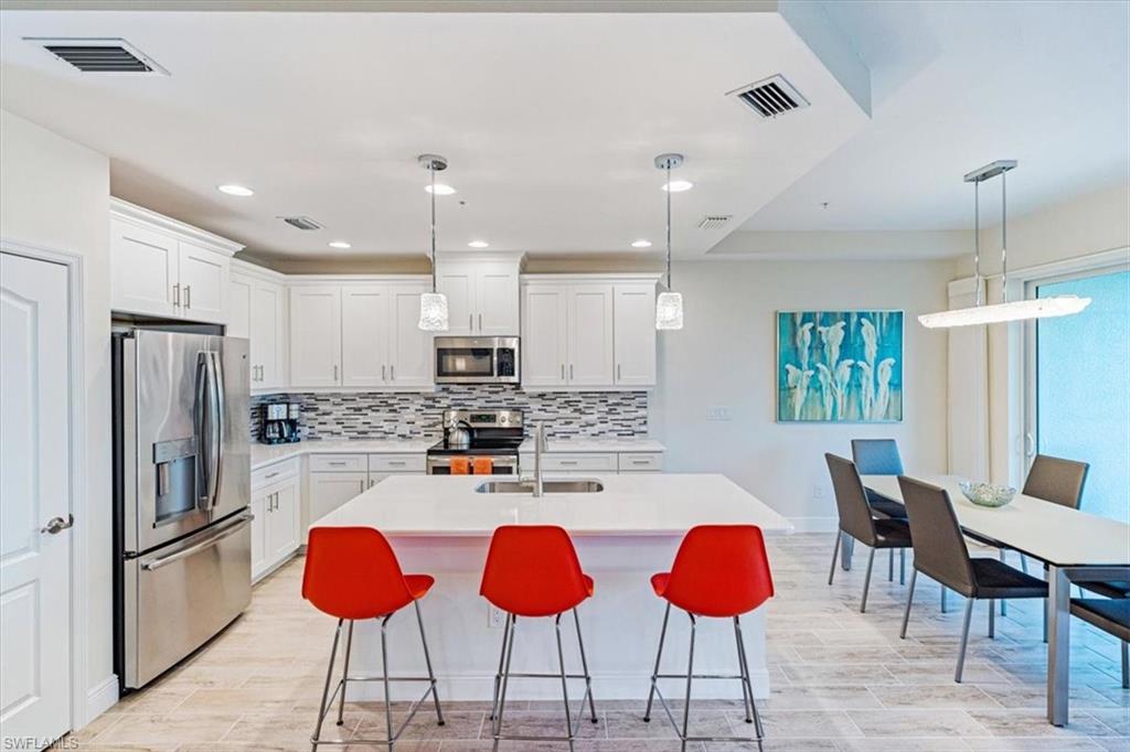 6934 Avalon Circle, Unit 402 Naples, FL 34112 - Photo 8 of 28 a kitchen with stainless steel appliances kitchen island granite countertop a refrigerator a stove a dining table and chairs with wooden floor