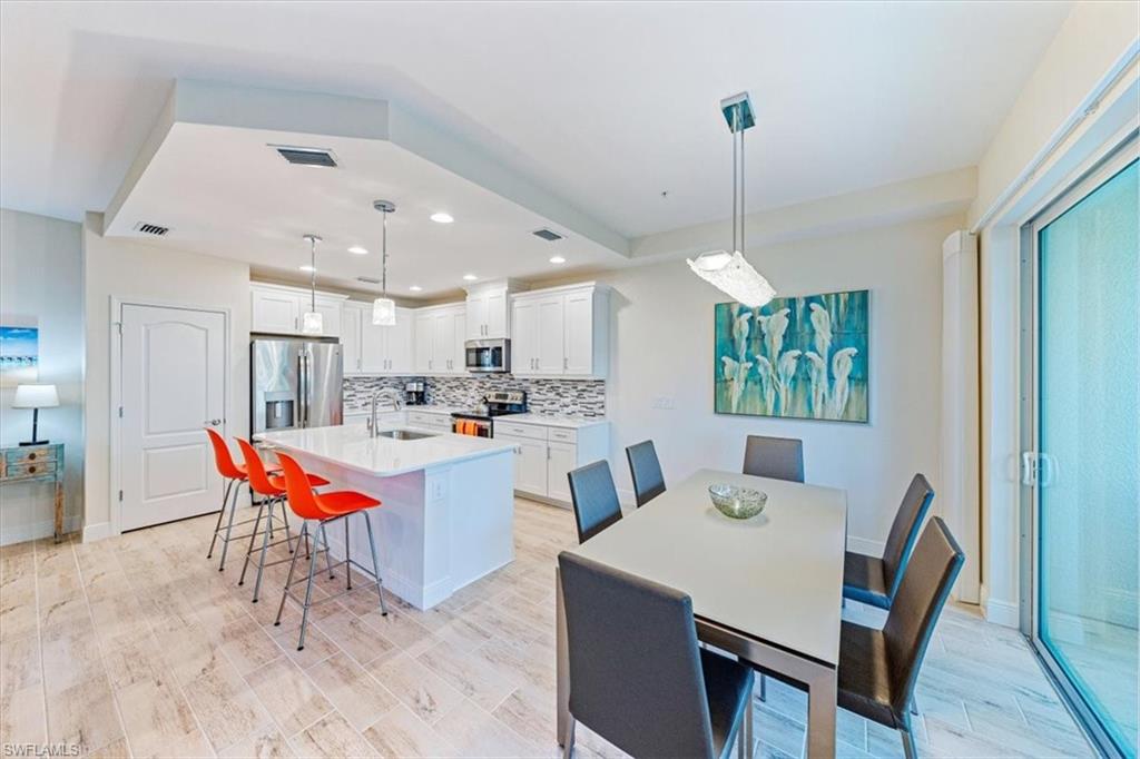 6934 Avalon Circle, Unit 402 Naples, FL 34112 - Photo 10 of 28 a kitchen with a dining table chairs and white cabinets