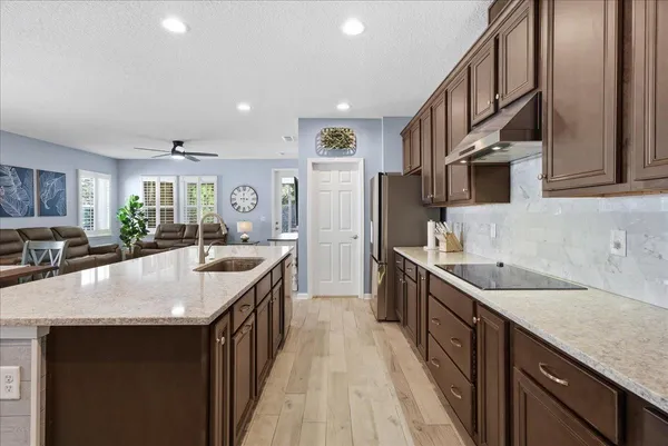 a kitchen with stainless steel appliances granite countertop a stove a refrigerator a sink a dining table and chairs with wooden floor