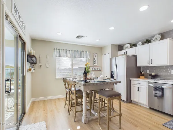 a kitchen with stainless steel appliances kitchen island granite countertop a refrigerator a stove a sink and white cabinets with wooden floor