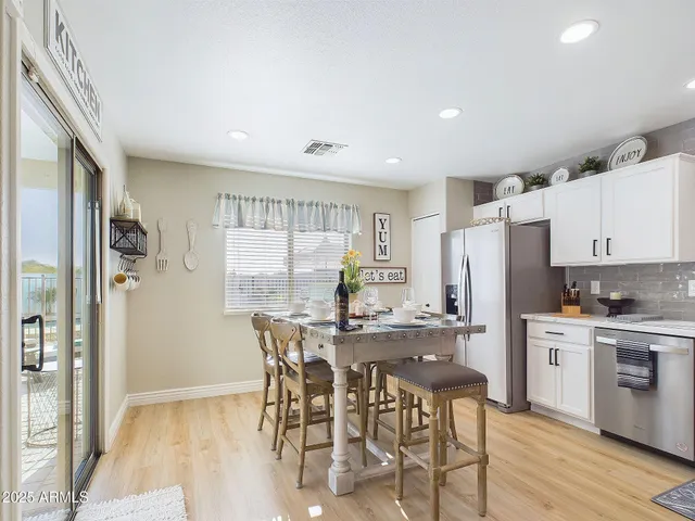 a kitchen with stainless steel appliances kitchen island granite countertop a refrigerator a stove a sink and white cabinets with wooden floor