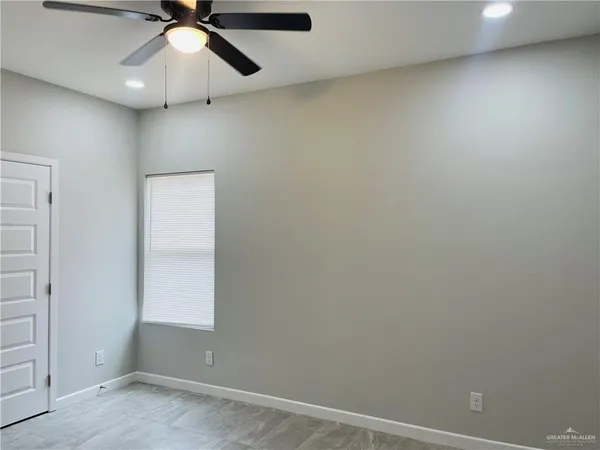 an empty room with a window and a fan