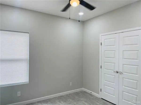 an empty room with a ceiling fan and wooden floor