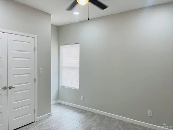 an empty room with a ceiling fan and wooden floor