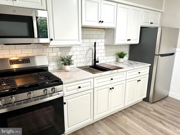a kitchen with white cabinets and appliances