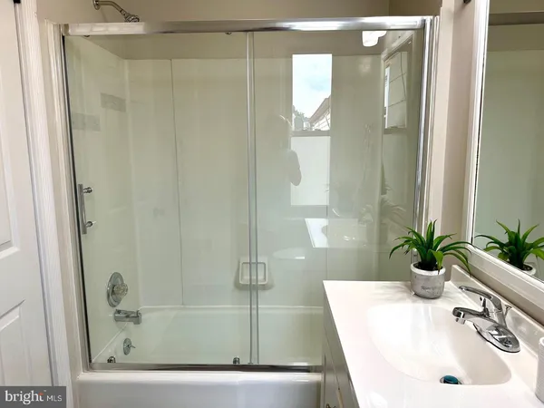 a bathroom with a sink a glass door a shower and a mirror