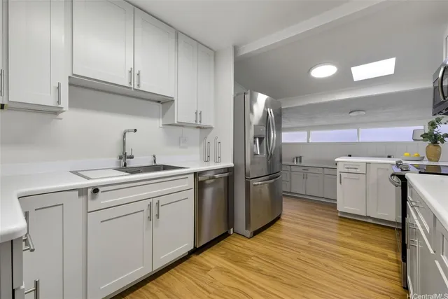 a kitchen with a sink cabinets stainless steel appliances and a window
