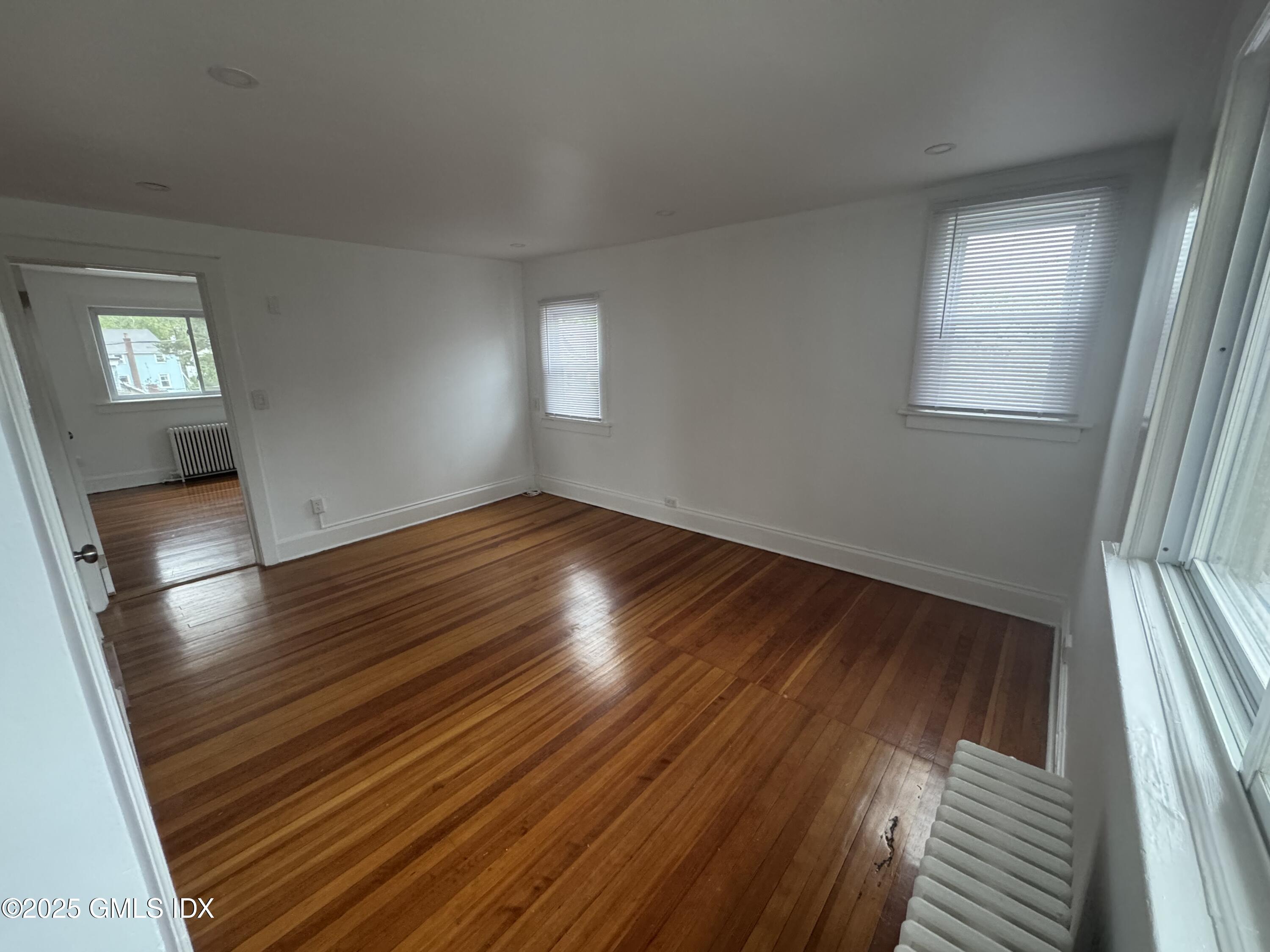 47 Cos Cob Avenue, Unit 3 Cos Cob, CT 06807 - Photo 6 of 12 an empty room with wooden floor and windows