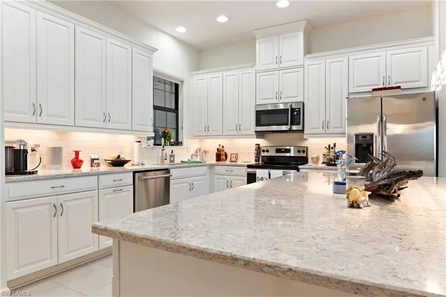 a kitchen with granite countertop a refrigerator sink and cabinets