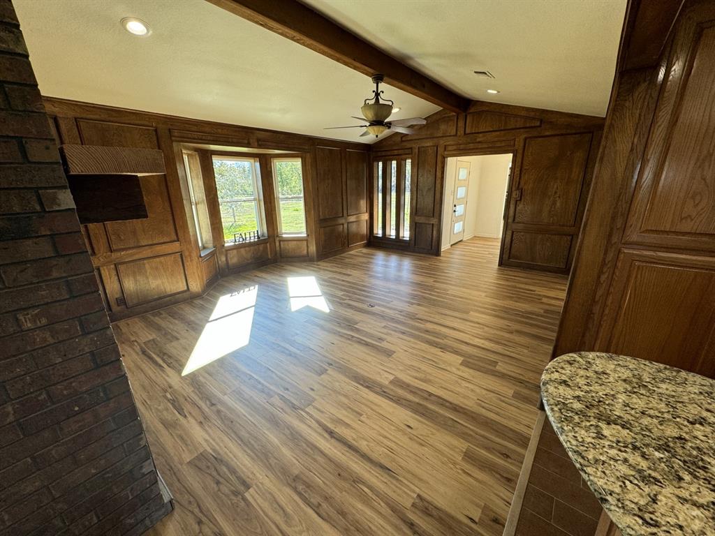 520 County Road Powderly, TX 75473 - Photo 13 of 24 Unfurnished living room with wooden walls, ceiling fan, lofted ceiling with beams, and dark hardwood / wood-style floors