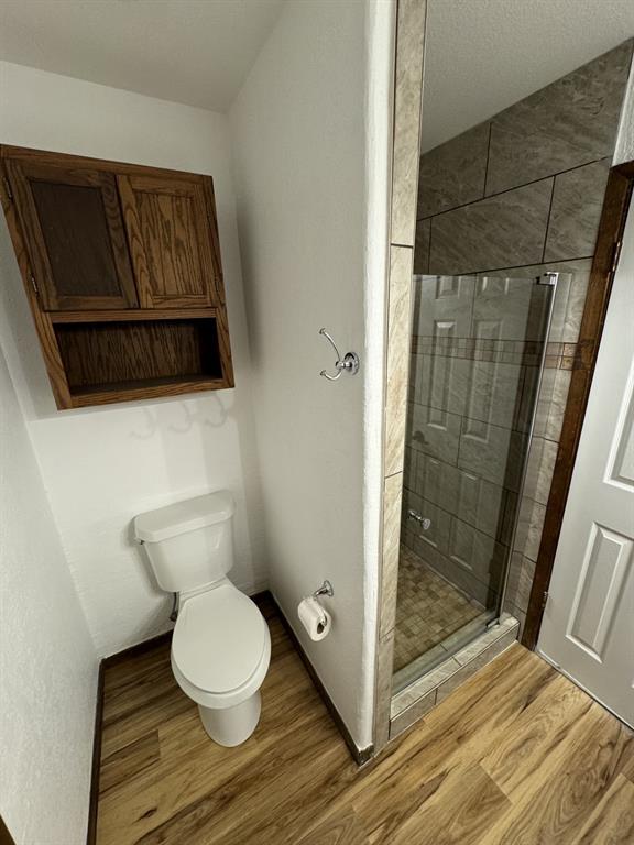 520 County Road Powderly, TX 75473 - Photo 20 of 24 Bathroom featuring a shower with door, wood-type flooring, and toilet