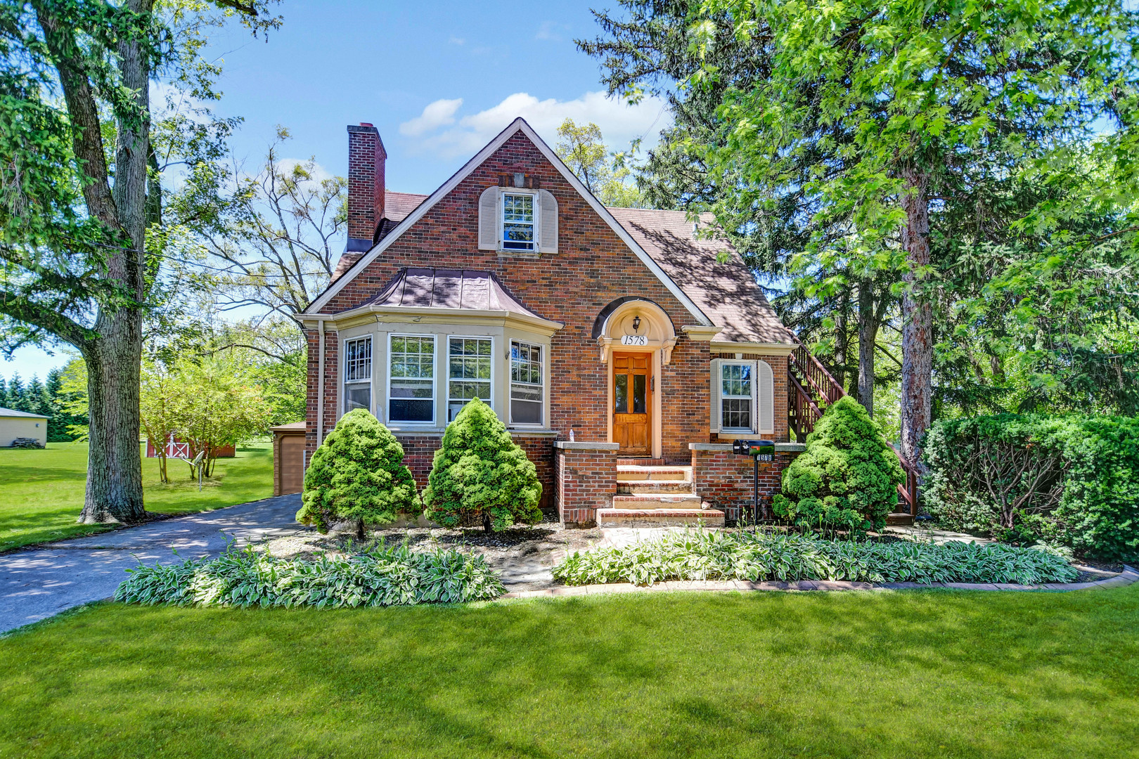 a front view of a house with a yard and green space