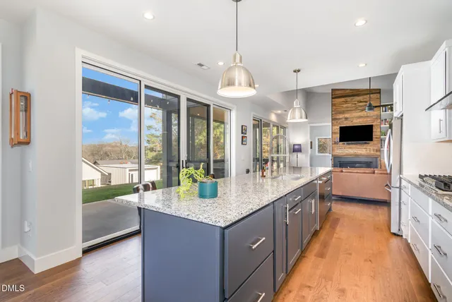 a large kitchen with kitchen island granite countertop a large window and stainless steel appliances