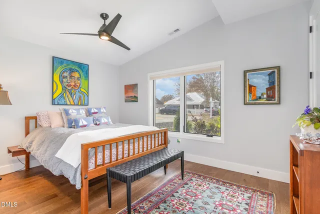 a bedroom with a bed a painting on the wall and a baby crib