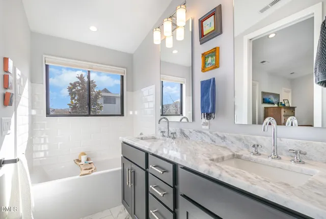a bathroom with a granite countertop sink mirror and bathtub