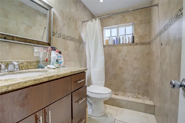 a bathroom with a granite countertop sink toilet a mirror and shower