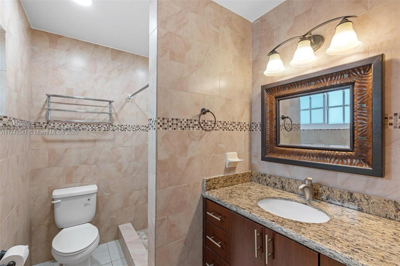 4995 Ponce De Leon Coral Gables, FL 33146 - Photo 48 of 92 a bathroom with a granite countertop sink a toilet and a mirror