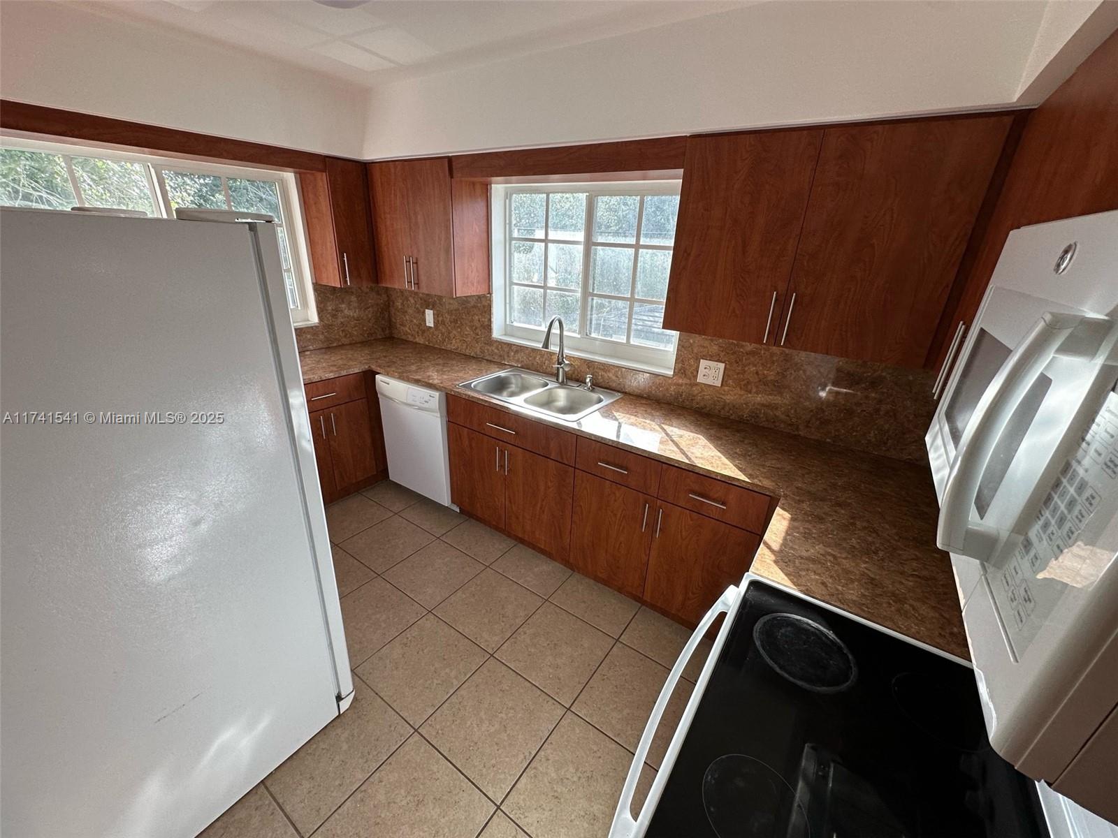 4995 Ponce De Leon Coral Gables, FL 33146 - Photo 60 of 92 a kitchen with granite countertop a refrigerator and a sink