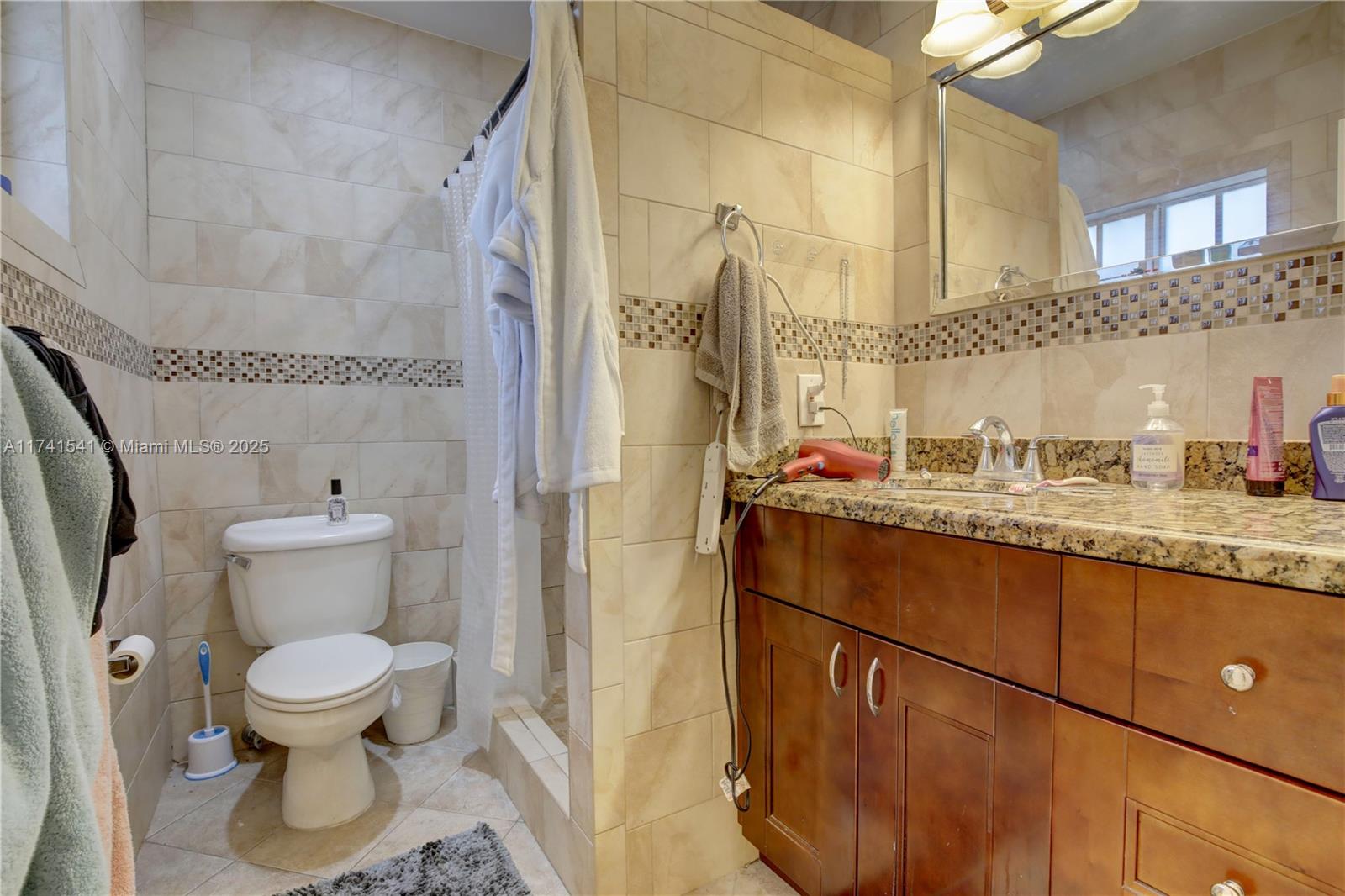 4995 Ponce De Leon Coral Gables, FL 33146 - Photo 80 of 92 a bathroom with a granite countertop toilet sink and mirror