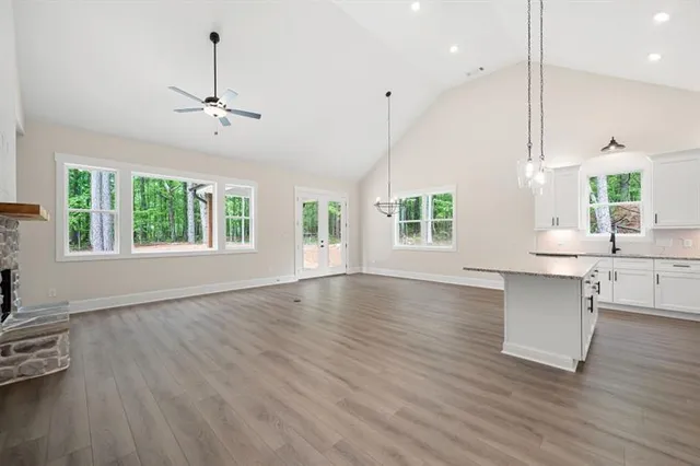 a kitchen with stainless steel appliances granite countertop a sink a stove a refrigerator and island with wooden floor