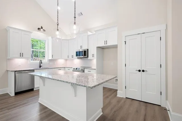 a kitchen with stainless steel appliances granite countertop wooden cabinets a sink a window and a counter