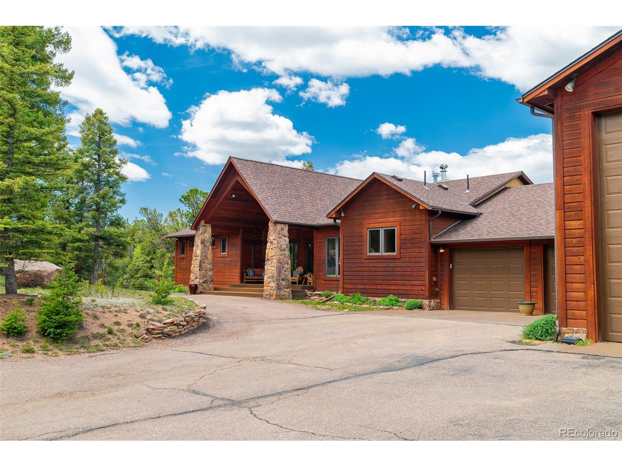 2755 Elk Ridge Divide Divide, CO 80814 - Photo 5 of 50 View of front of house with garage, shop entrance, and level, circular driveway around center landscape feature
