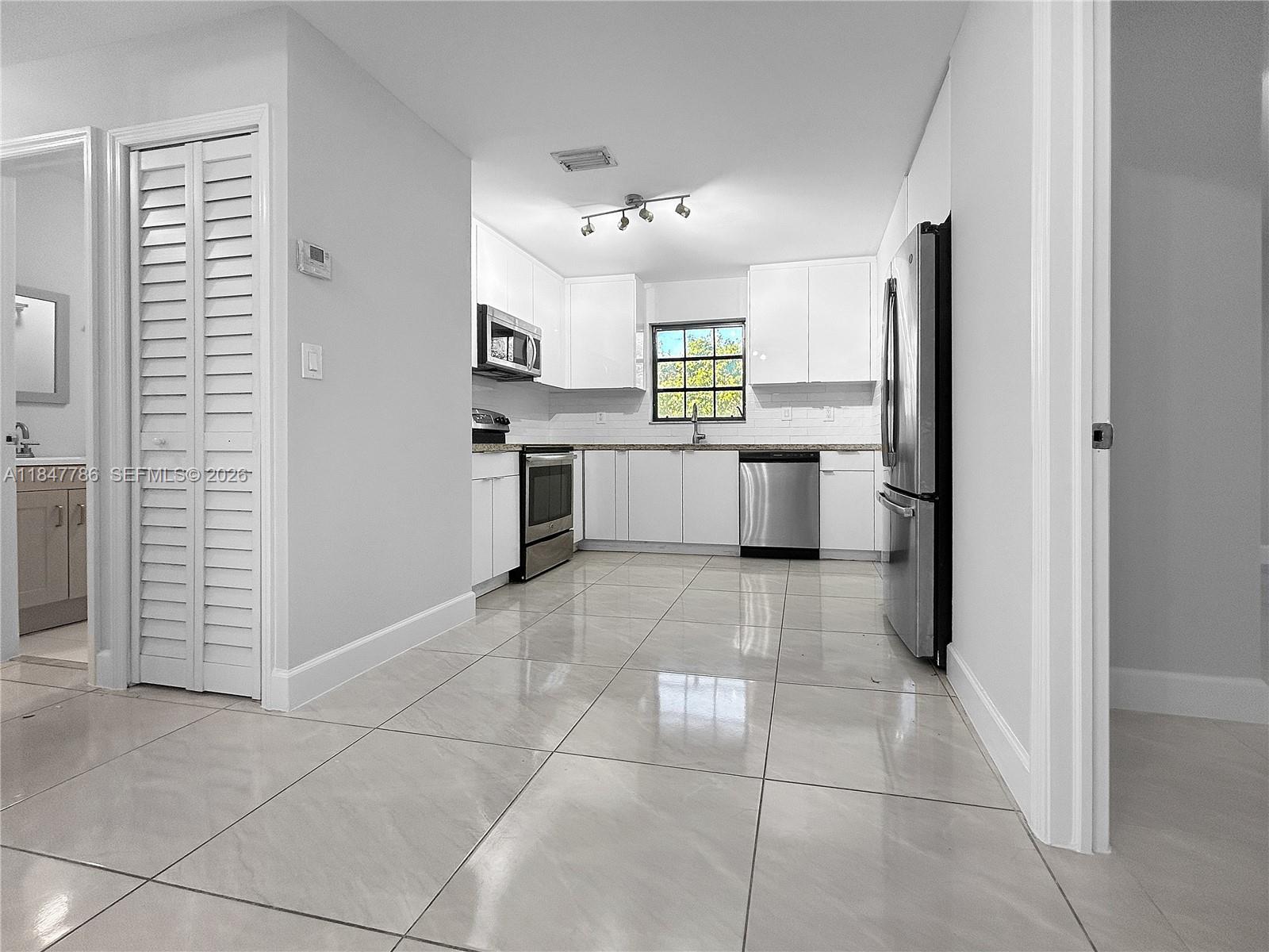 13925 Southwest 26th Terrace Miami, FL 33175 - Photo 12 of 42 a large white kitchen with a refrigerator a stove a microwave and cabinets