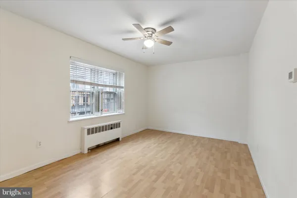 an empty room with chandelier fan and windows