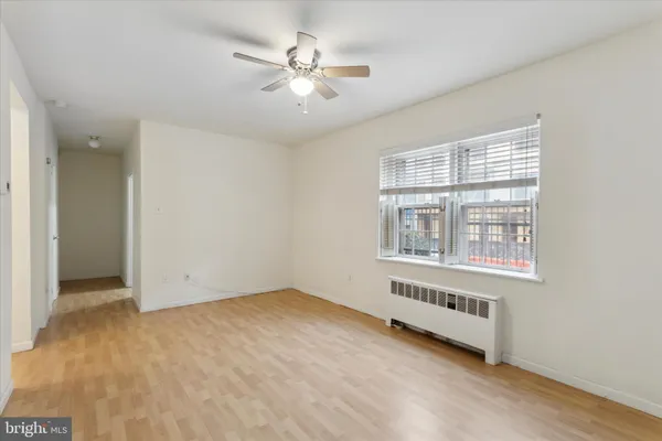 an empty room with chandelier fan and windows