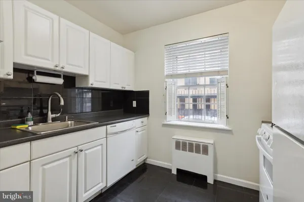 a kitchen with white cabinets and a window