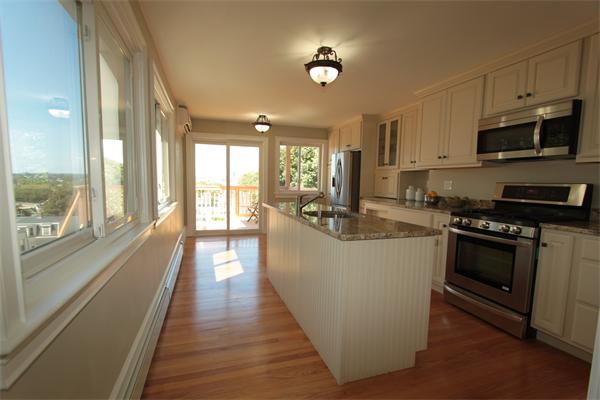 a view of a kitchen with kitchen island a large window a sink and stainless steel appliances