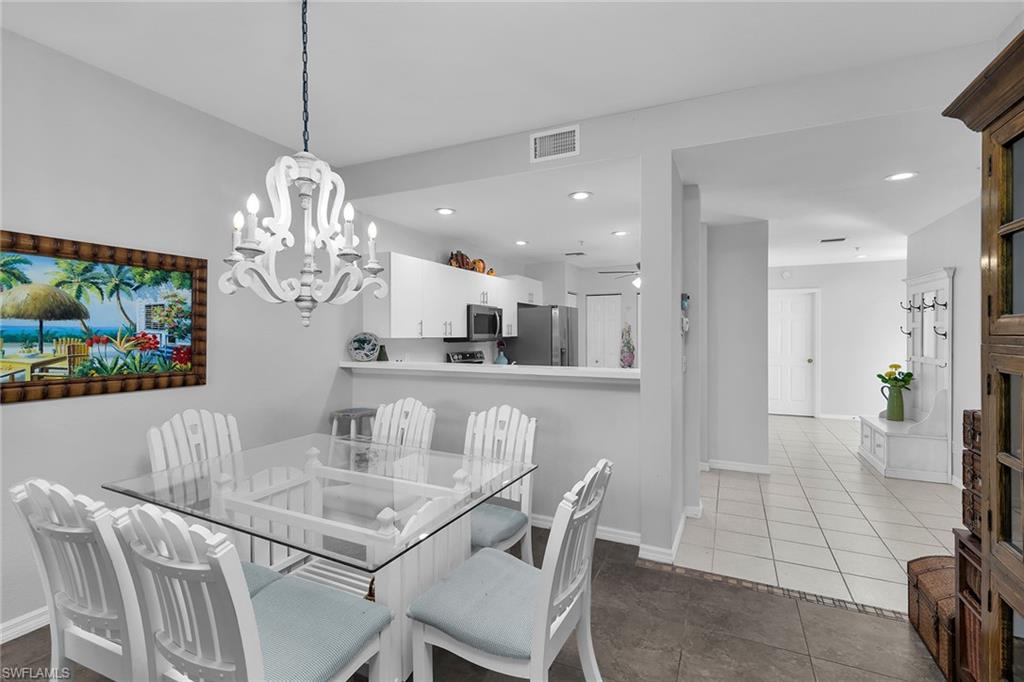 8345 Whisper Trace Way, Unit 102 Naples, FL 34114 - Photo 7 of 25 a view of a dining room with furniture a chandelier and wooden floor