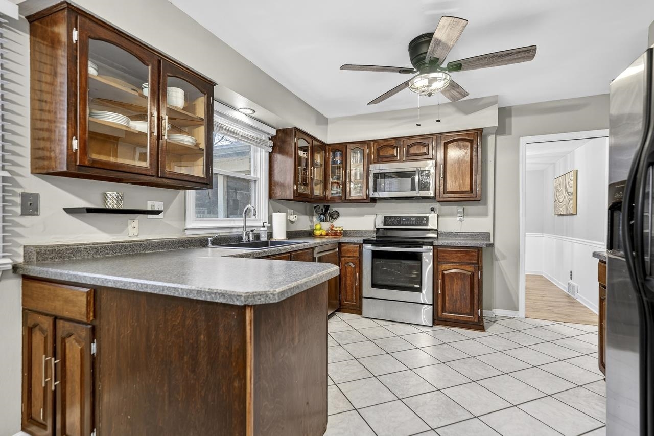 4966 Brigadoon Road Rockford, IL 61107 - Photo 12 of 40 a kitchen with stainless steel appliances granite countertop a sink stove and a refrigerator