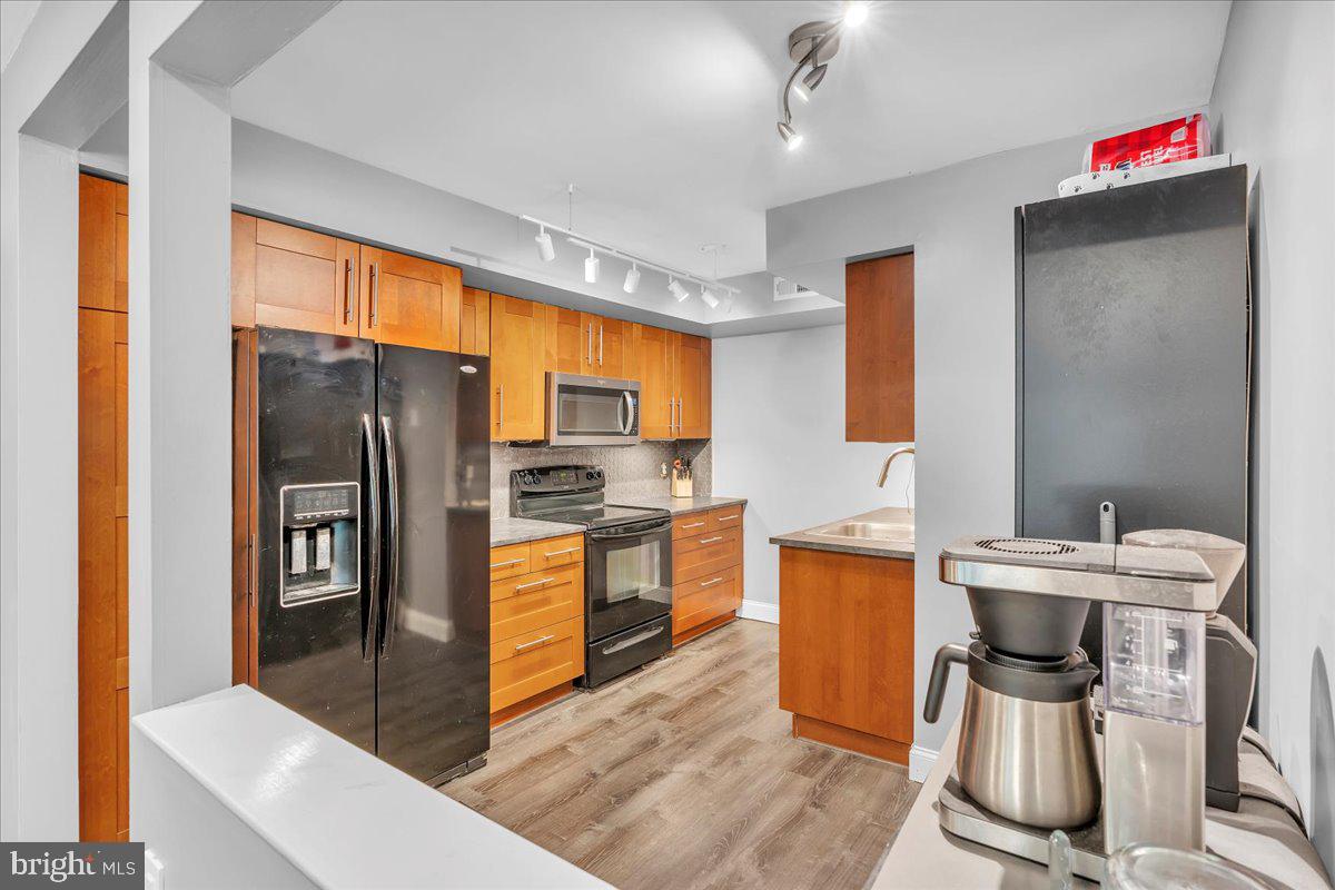 115 East Kings Highway, Unit 334 Maple Shade, NJ 08052 - Photo 8 of 26 a kitchen with stainless steel appliances granite countertop a refrigerator a stove top oven a sink dishwasher and wooden cabinets with wooden floor