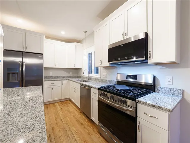 a kitchen with granite countertop a sink stainless steel appliances and white cabinets