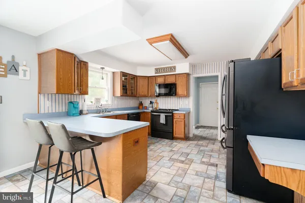 a kitchen with stainless steel appliances kitchen island granite countertop a refrigerator a stove top oven and a sink
