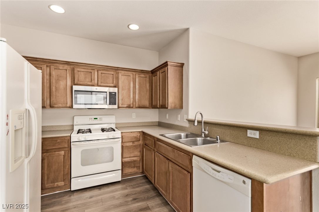 6224 Boulder Rise Street Las Vegas, NV 89115 - Photo 14 of 26 Kitchen with white appliances, light countertops, light wood-style floors, brown cabinetry, and recessed lighting