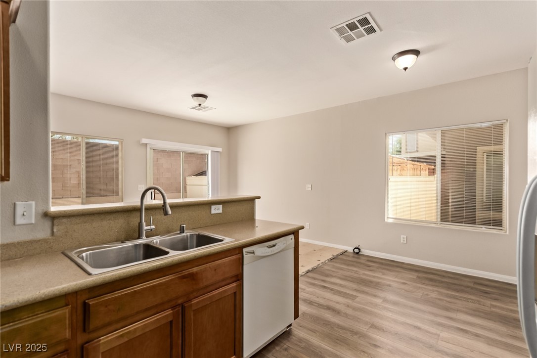 6224 Boulder Rise Street Las Vegas, NV 89115 - Photo 15 of 26 Kitchen featuring dishwasher, a peninsula, light wood finished floors, brown cabinetry, and light countertops