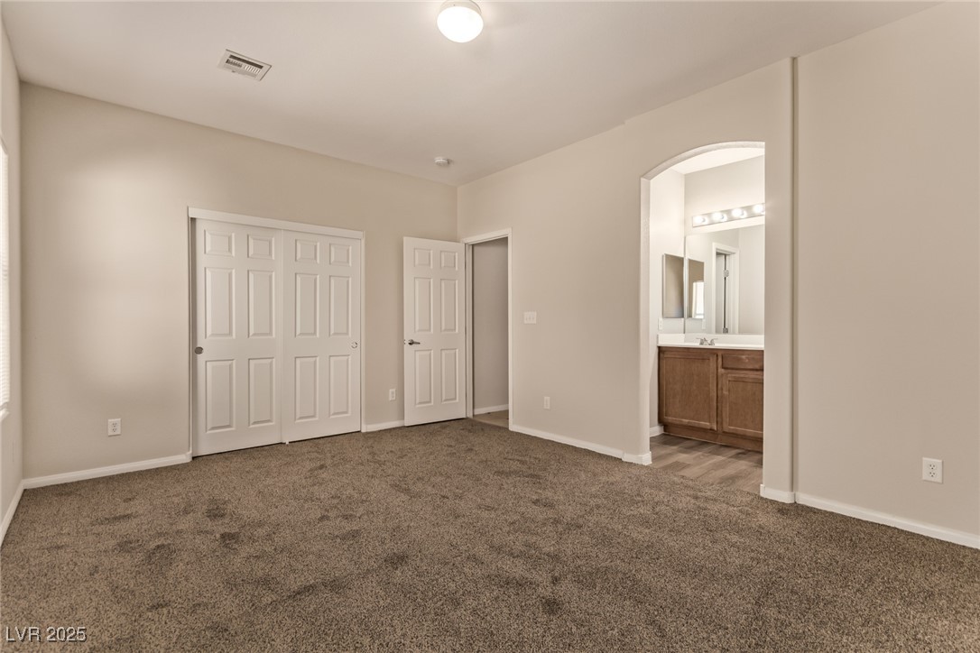 6224 Boulder Rise Street Las Vegas, NV 89115 - Photo 17 of 26 Unfurnished bedroom with dark carpet, a closet, arched walkways, and ensuite bath
