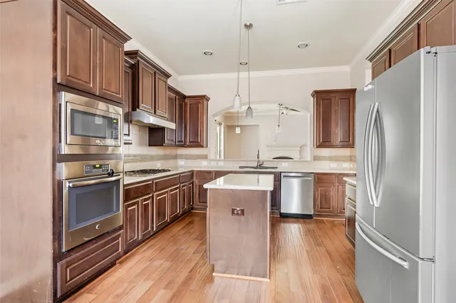 a kitchen with stainless steel appliances granite countertop a refrigerator a stove a sink dishwasher and white cabinets with wooden floor