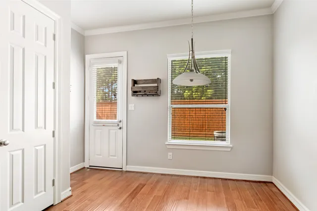 a view of an empty room with wooden floor and a window