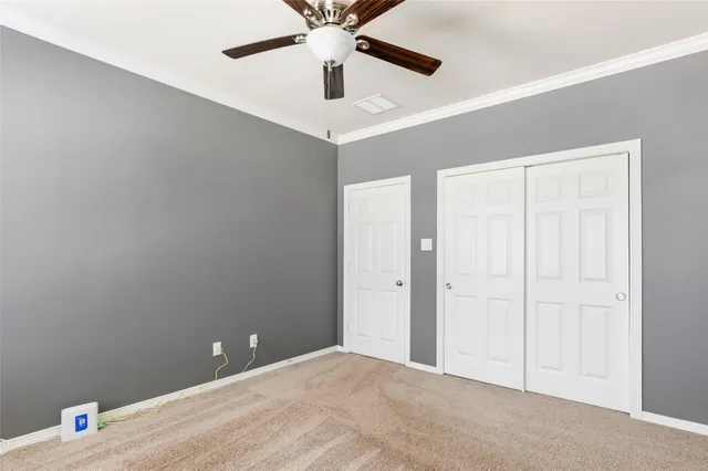 an empty room with ceiling fan and windows