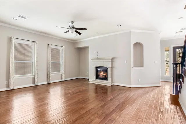a view of a livingroom with wooden floor a ceiling fan and windows