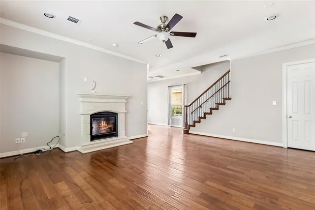 a view of an empty room with wooden floor a ceiling fan and a window