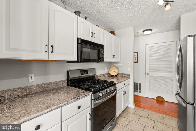 a kitchen with stainless steel appliances granite countertop a sink a stove a refrigerator a microwave and cabinets
