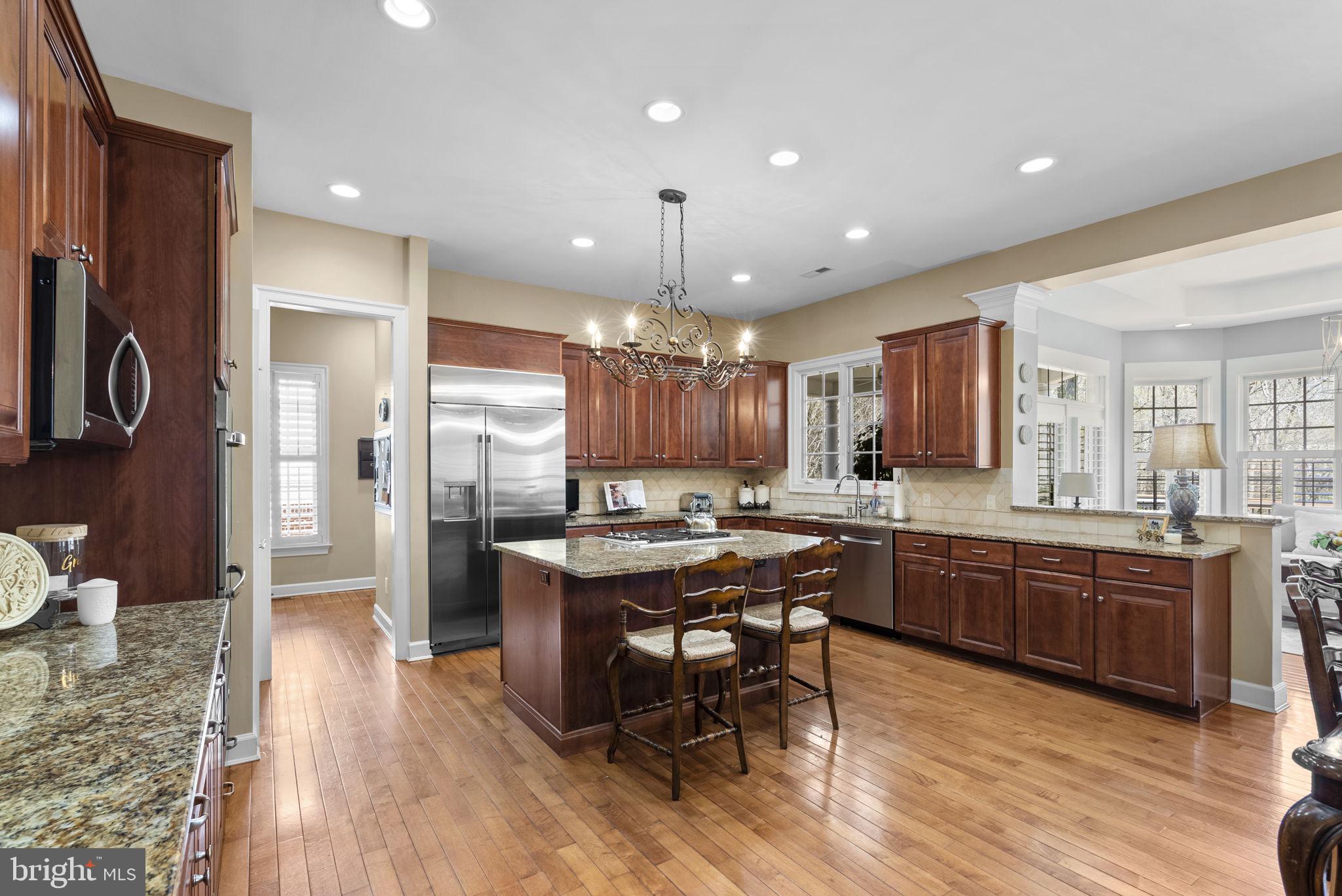 17516 Ashton Green Drive Sandy Spring, MD 20860 - Photo 23 of 60 a kitchen with stainless steel appliances granite countertop a refrigerator a sink dishwasher a dining table and chairs with wooden floor