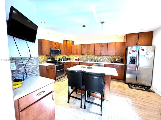 a kitchen with stainless steel appliances kitchen island granite countertop a table chairs and a refrigerator