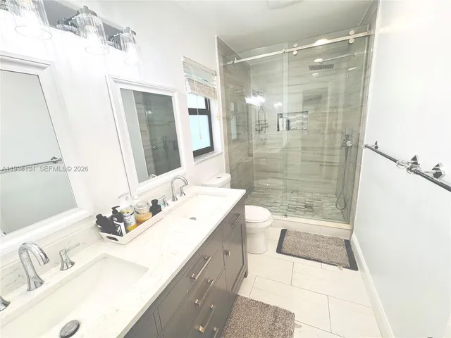 a bathroom with a granite countertop sink a toilet a mirror and shower